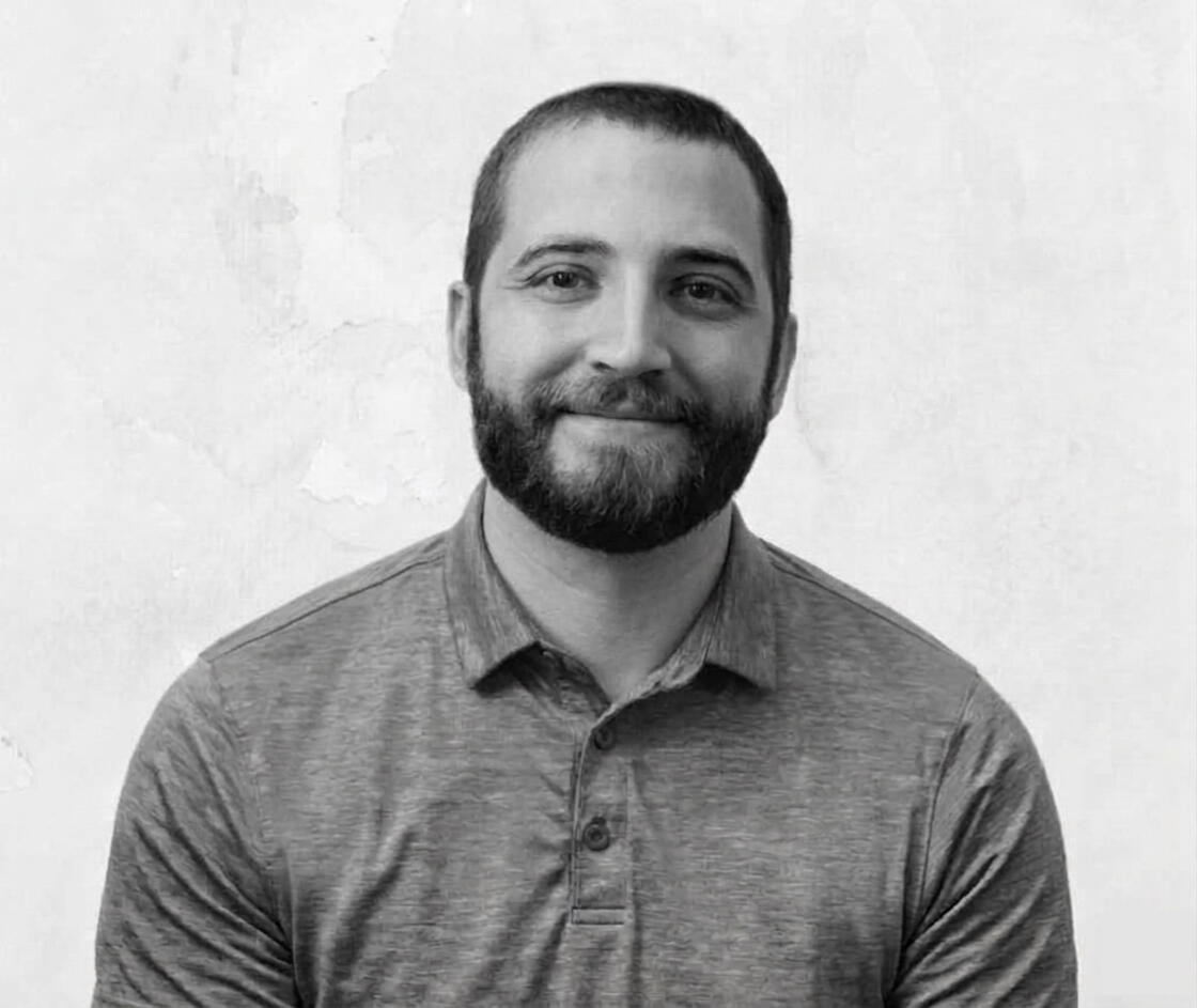 A man smiling in a black and white image.